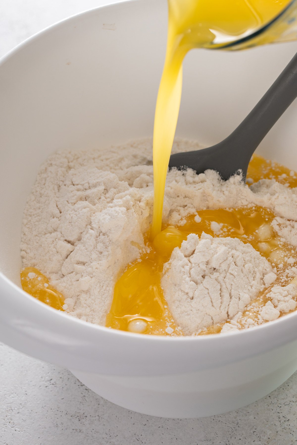 Melted butter being added to cake mix in a bowl.
