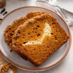 Two slices of pumpkin cream cheese bread on a plate.