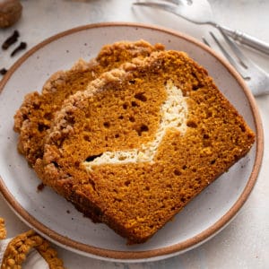 Two slices of pumpkin cream cheese bread on a plate.