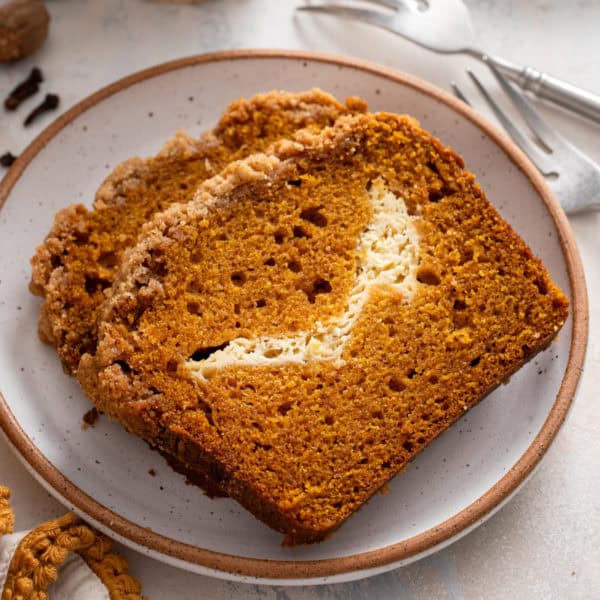 Two slices of pumpkin cream cheese bread on a plate.