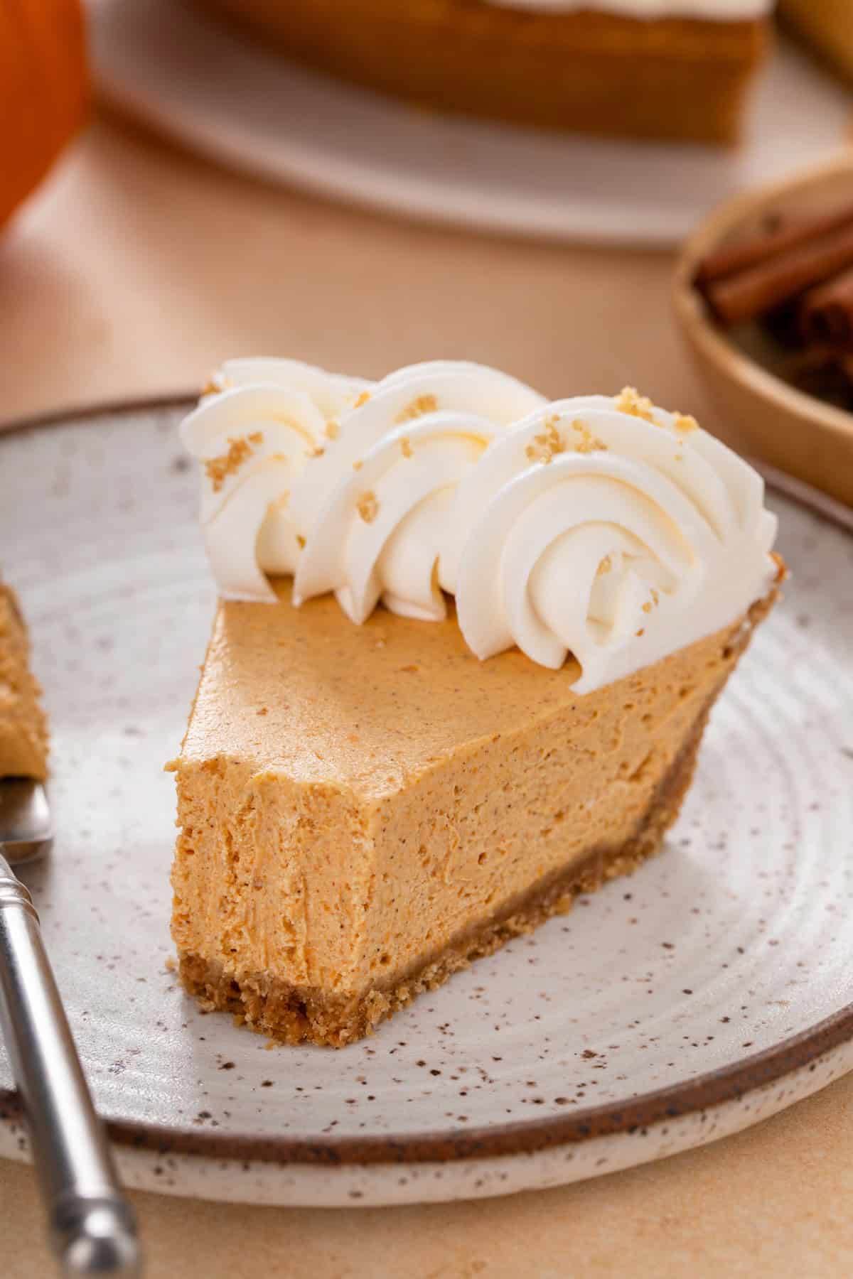 Bite taken from a slice of no-bake pumpkin cheesecake pie on a plate.