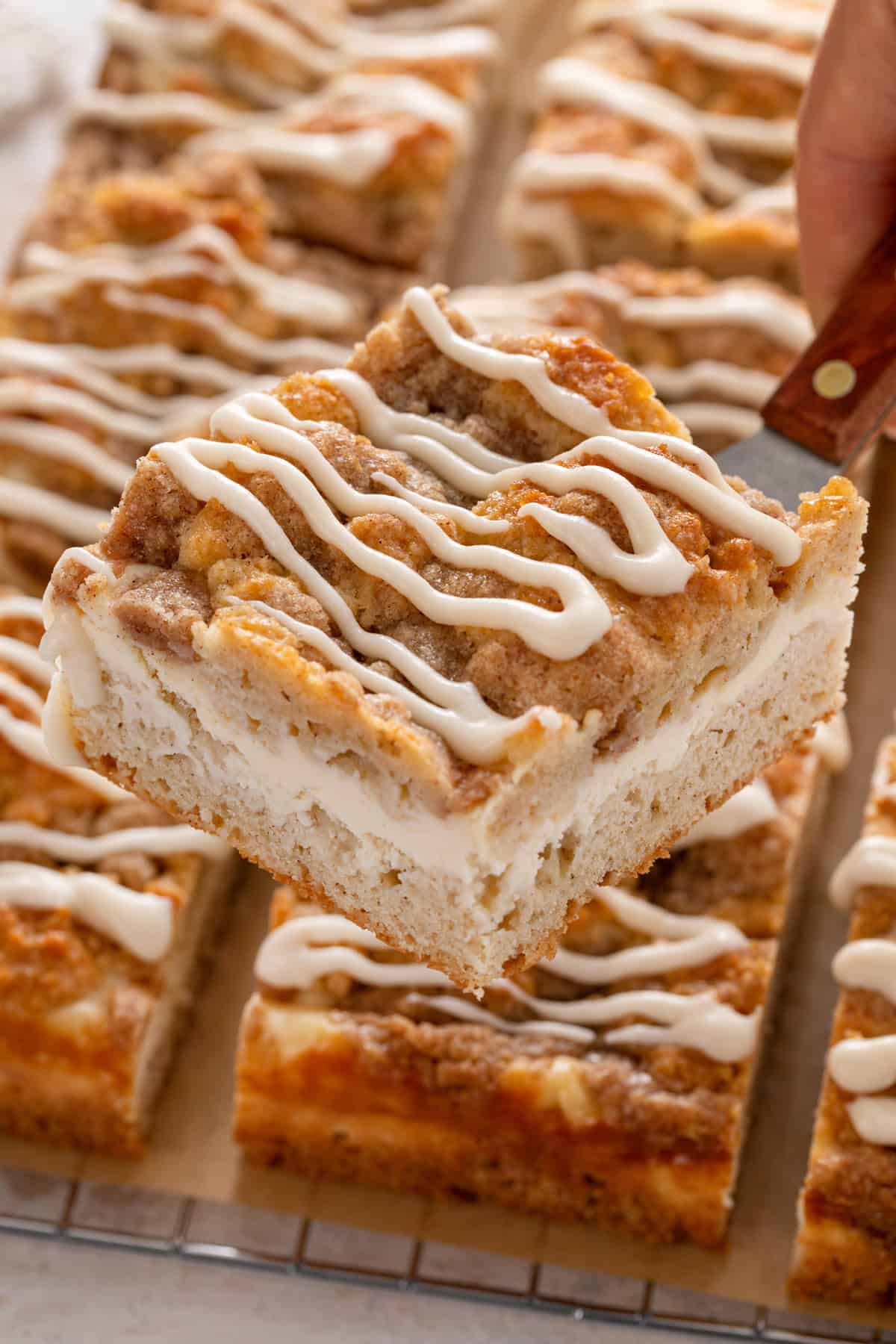 Cake server lifting up a slice of cream cheese coffee cake.