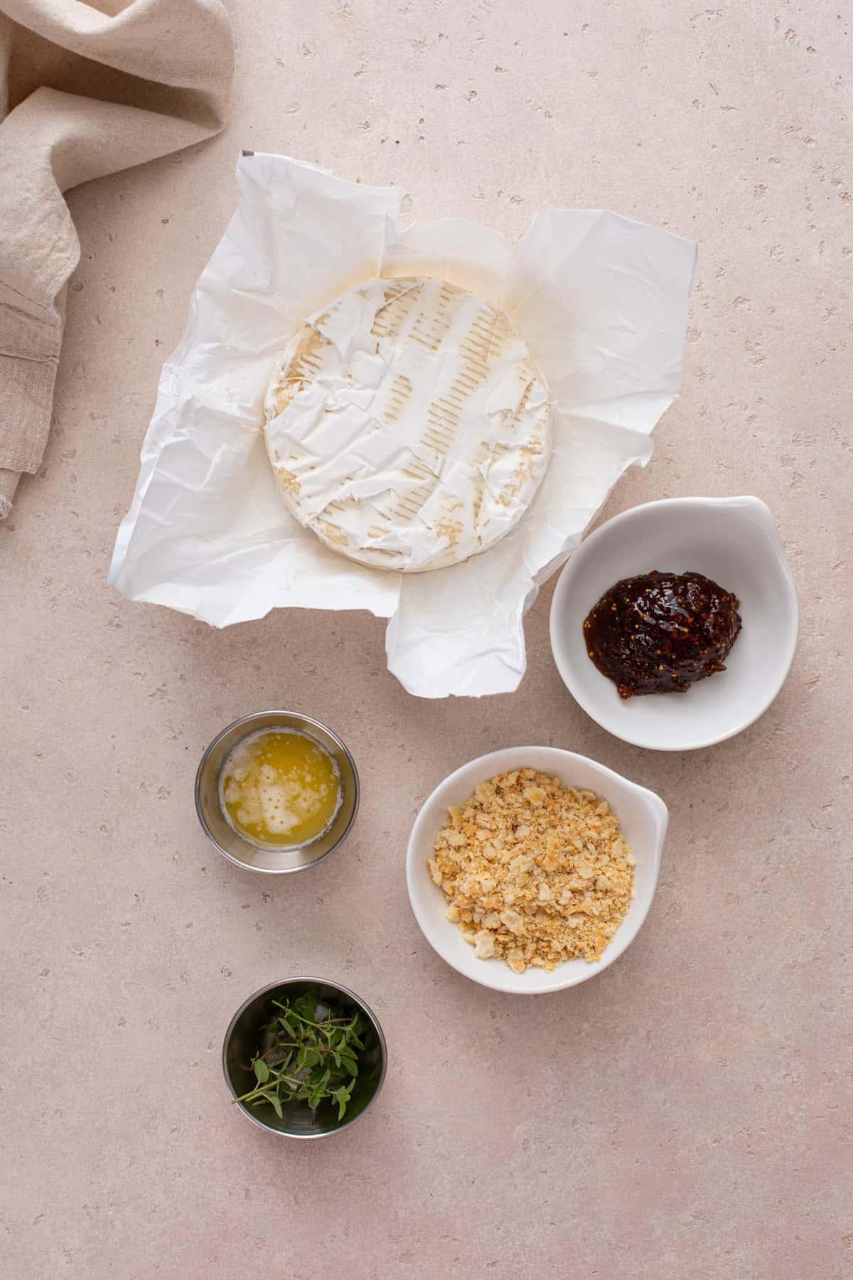 Ingredients for baked brie with jam arranged on a countertop.