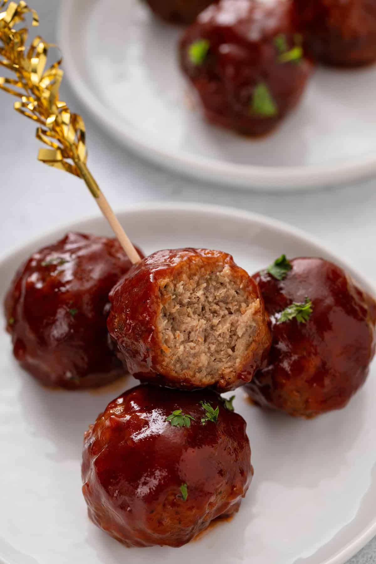 Bite taken from a cranberry meatball on an appetizer toothpick.