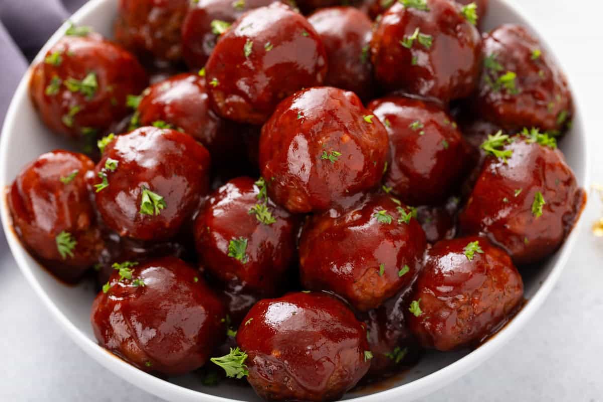 Close up of cranberry meatballs in a white bowl.