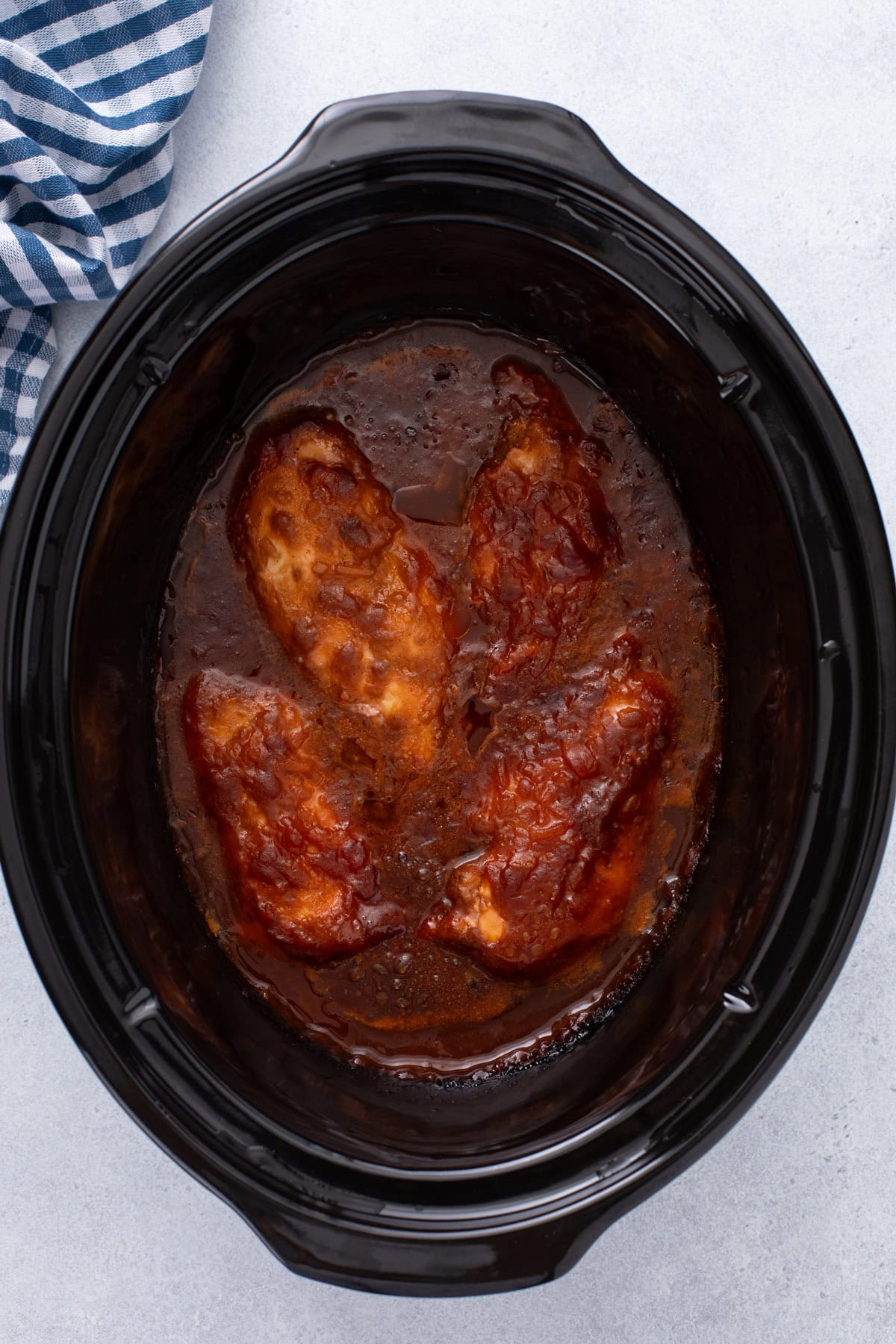 Cooked cranberry chicken in the crock of a slow cooker.
