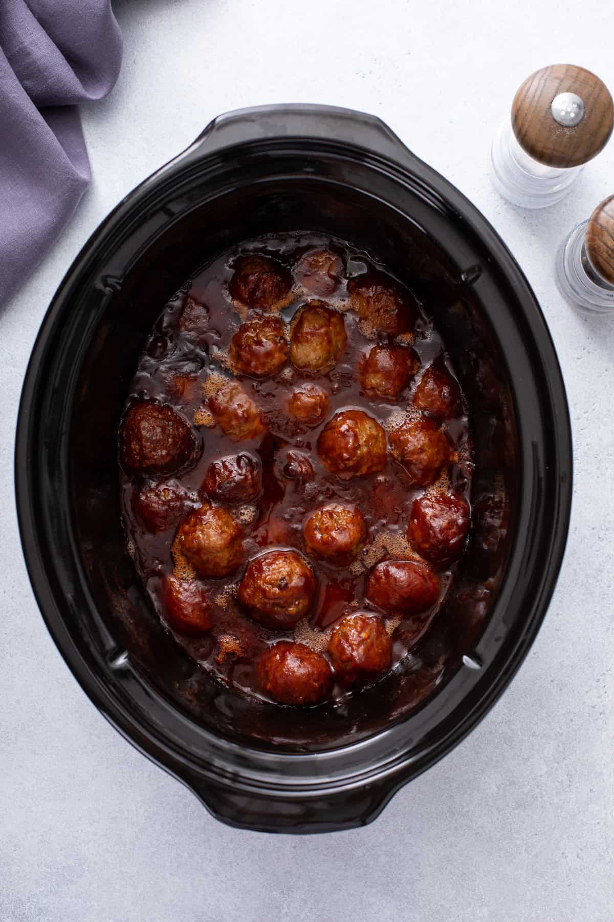 Cooked cranberry meatballs in a slow cooker.