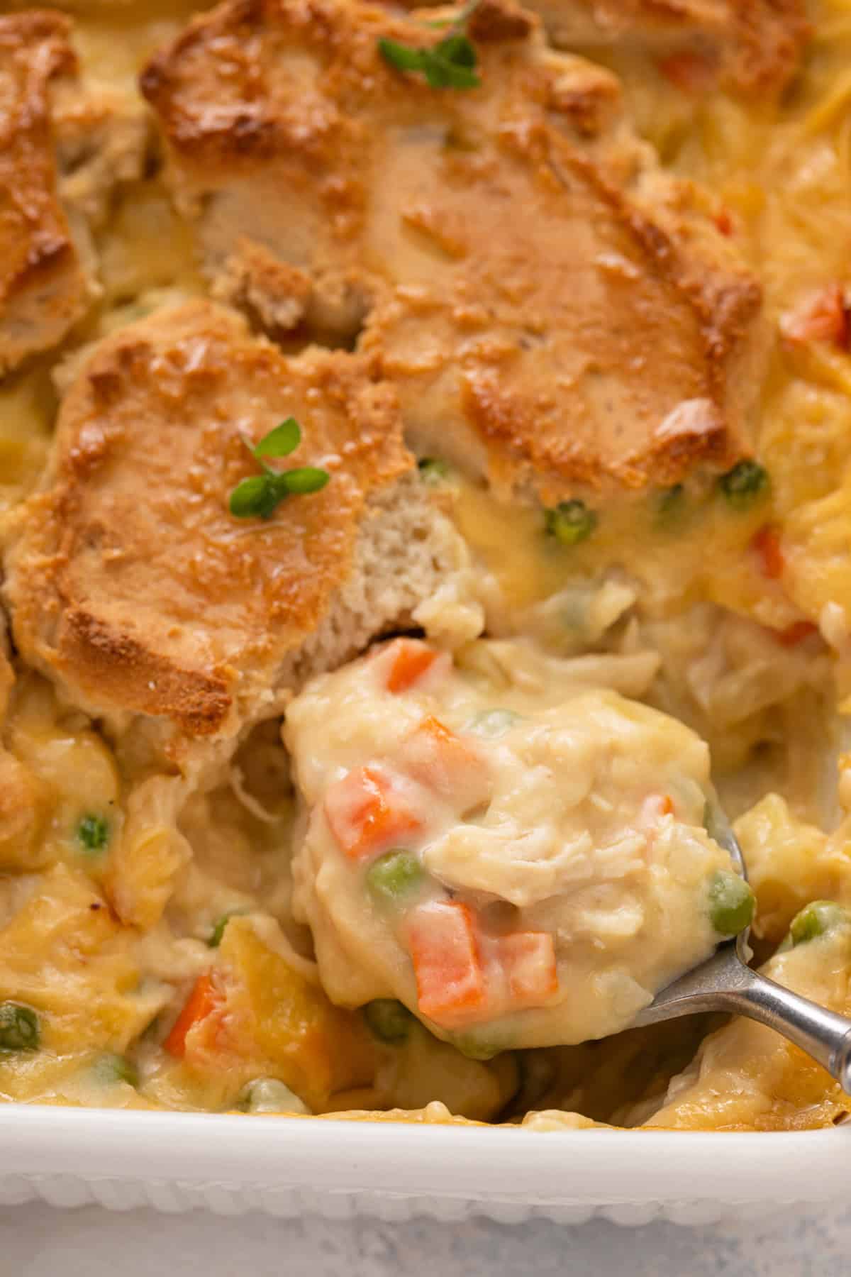 Spoon about to scoop up a serving of bisquick chicken pot pie from a baking dish.