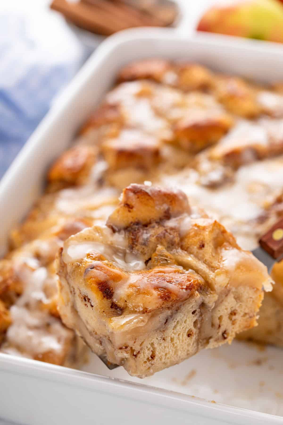 Slice of cinnamon roll casserole being lifted up by a cake server.