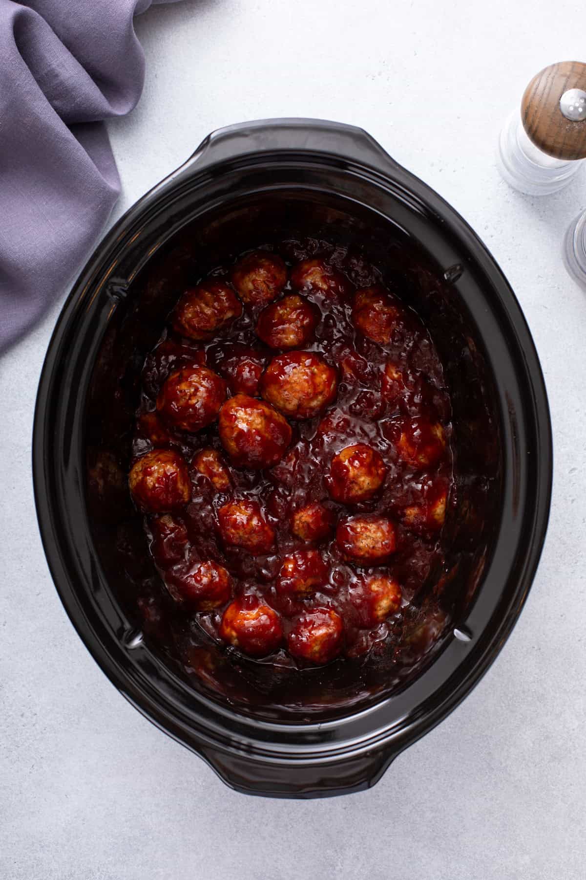 Uncooked cranberry meatballs in a slow cooker.