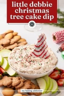 Bowl of christmas tree cake dip on a platter surrounded by cookies and fresh fruit. Text overlay includes recipe name.