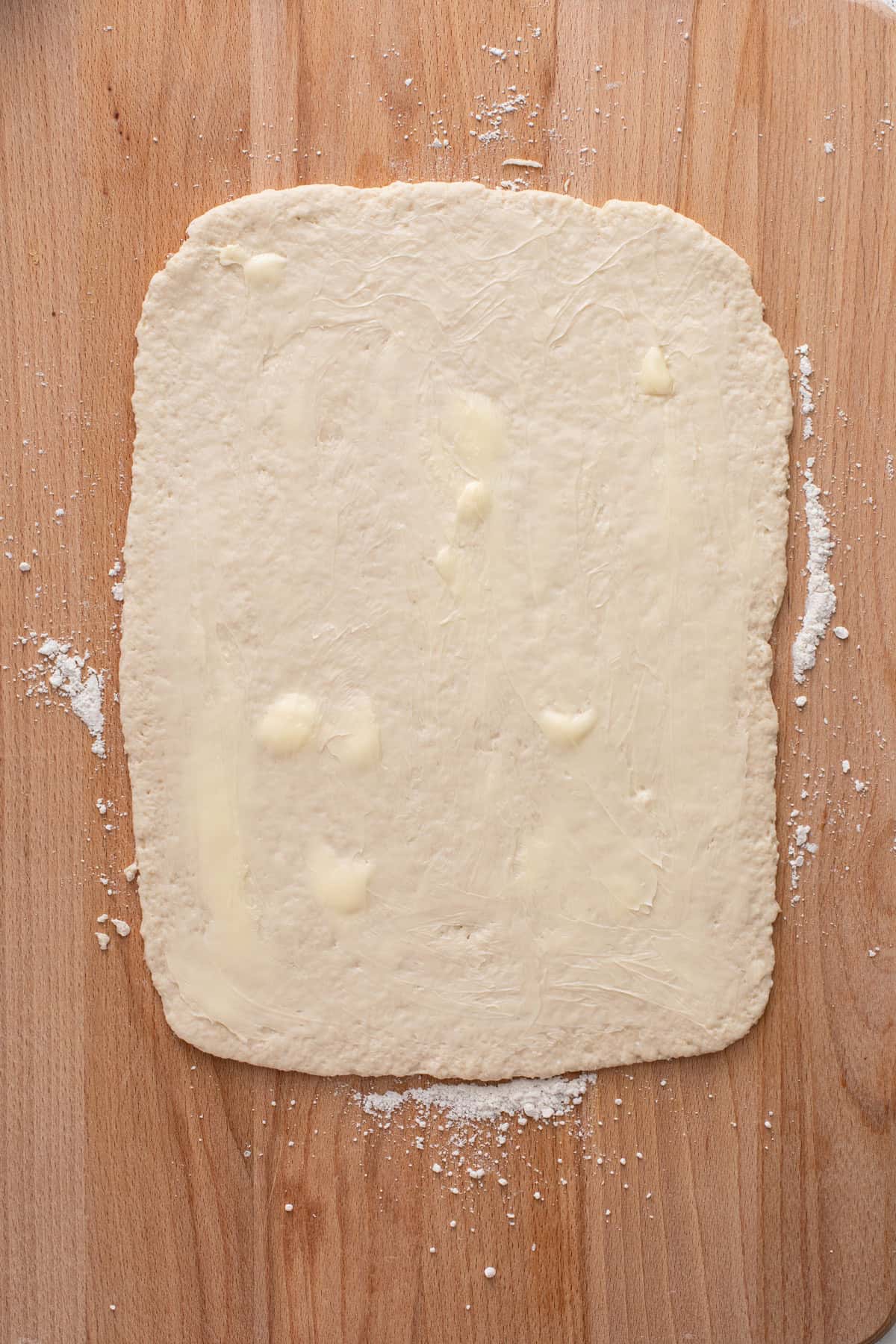 Rolled out biscuit dough spread with softened butter.