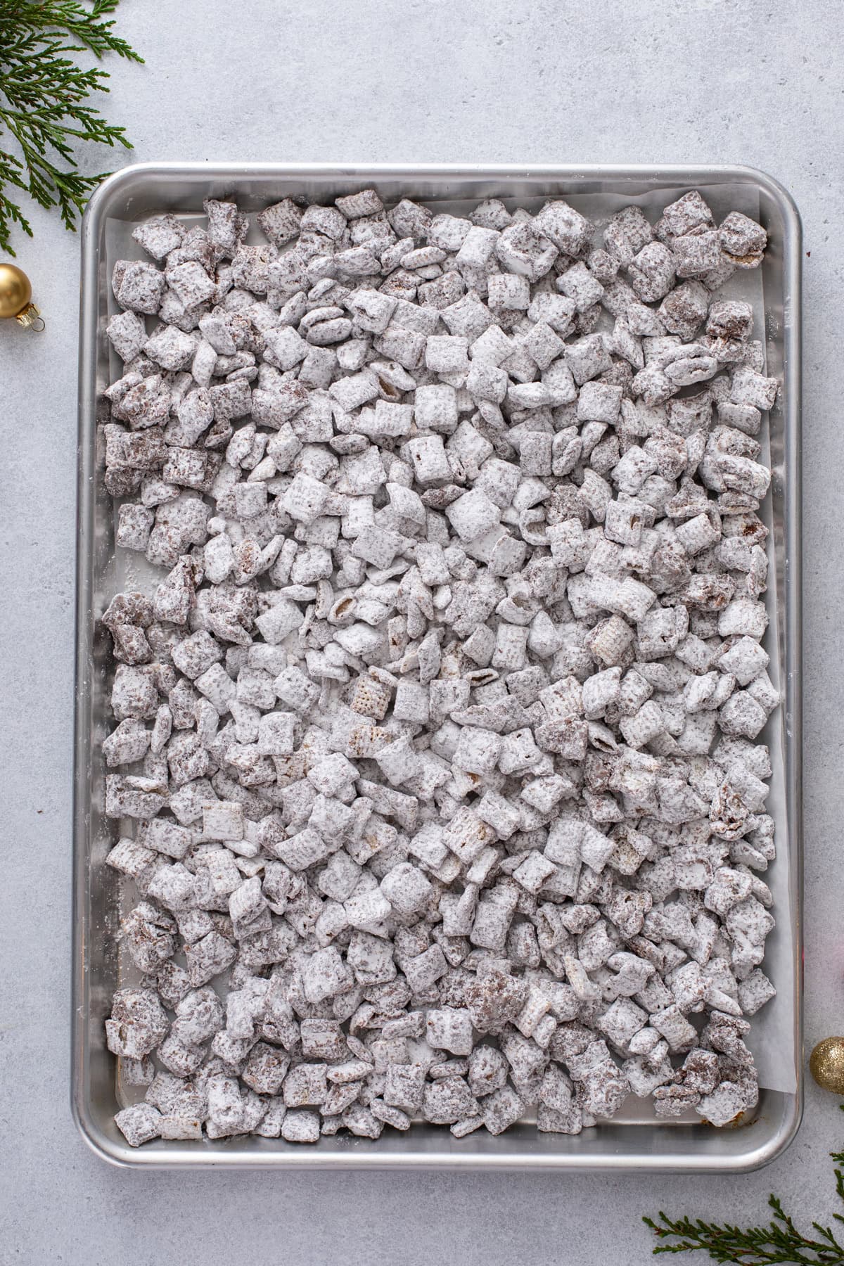 Coated cereal for reindeer chow spread out on a baking sheet to cool.