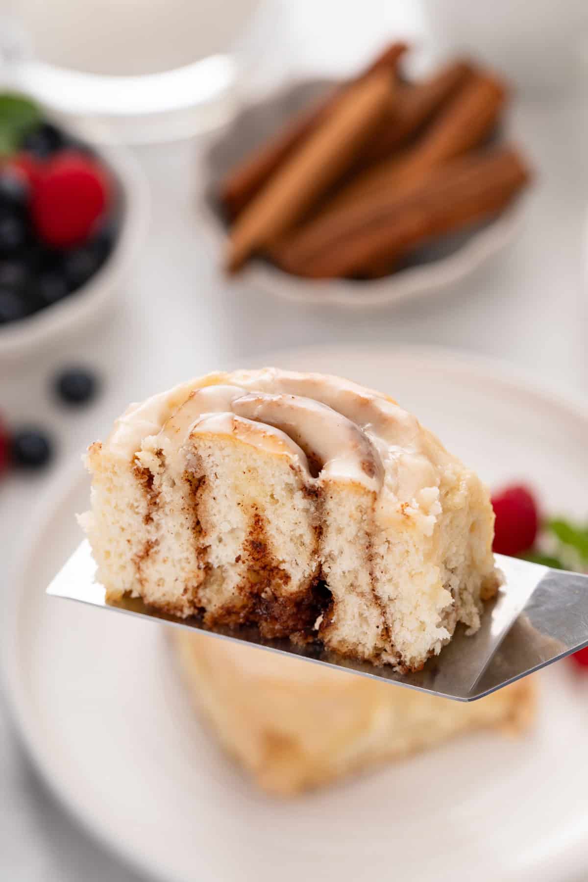 Halved biscuit cinnamon roll being held up with a cake server to show the inside texture.