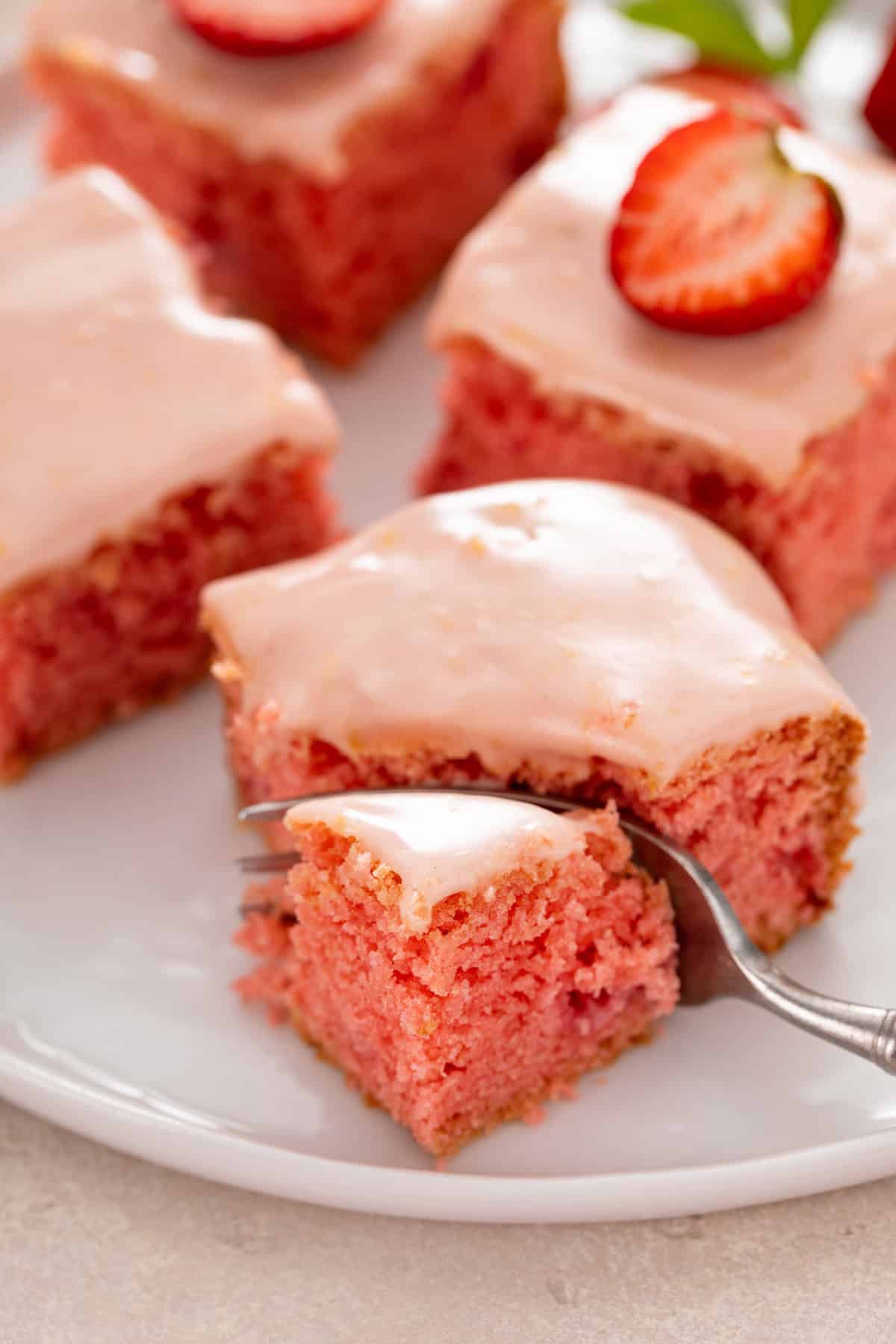 Fork cutting a bite from the corner of a strawberry brownie.