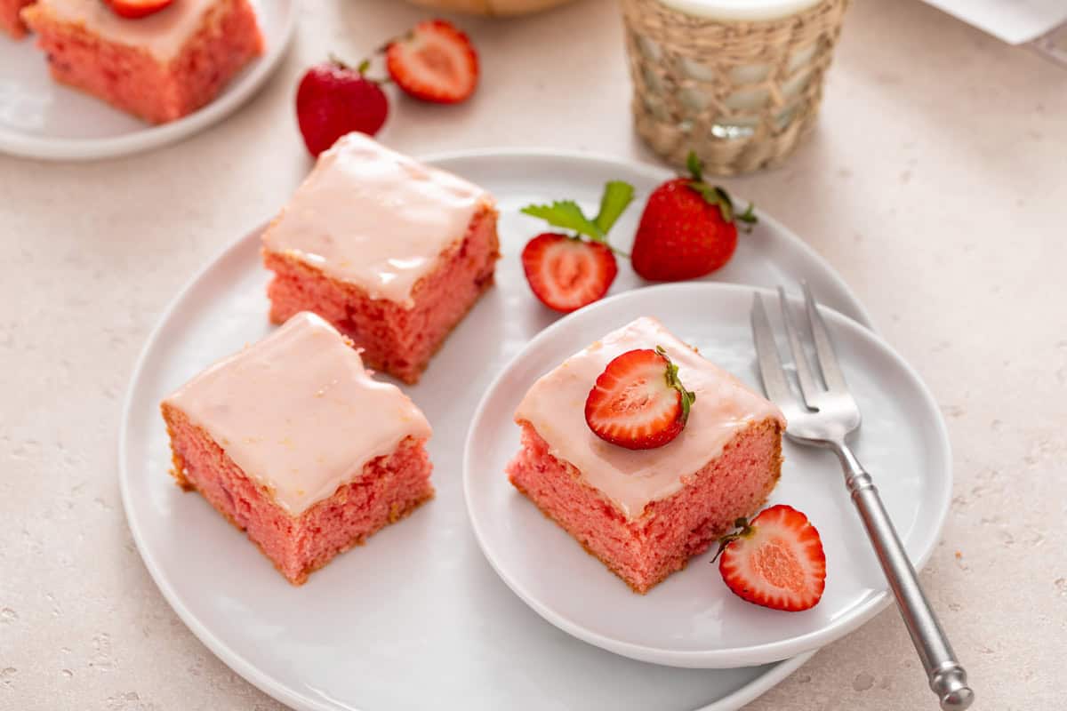 Three plated strawberry brownies with a glass of milk in the background.