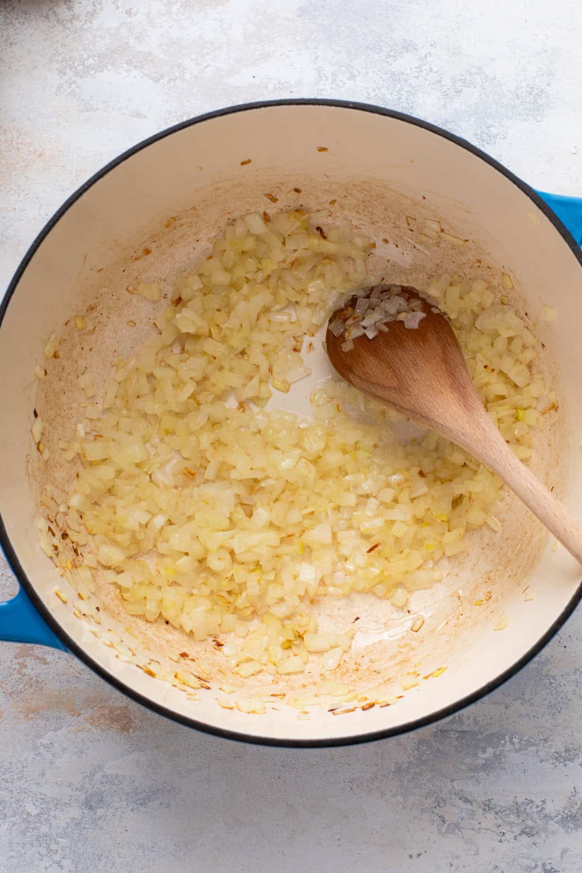 Stirring sauteed onions in a dutch oven.