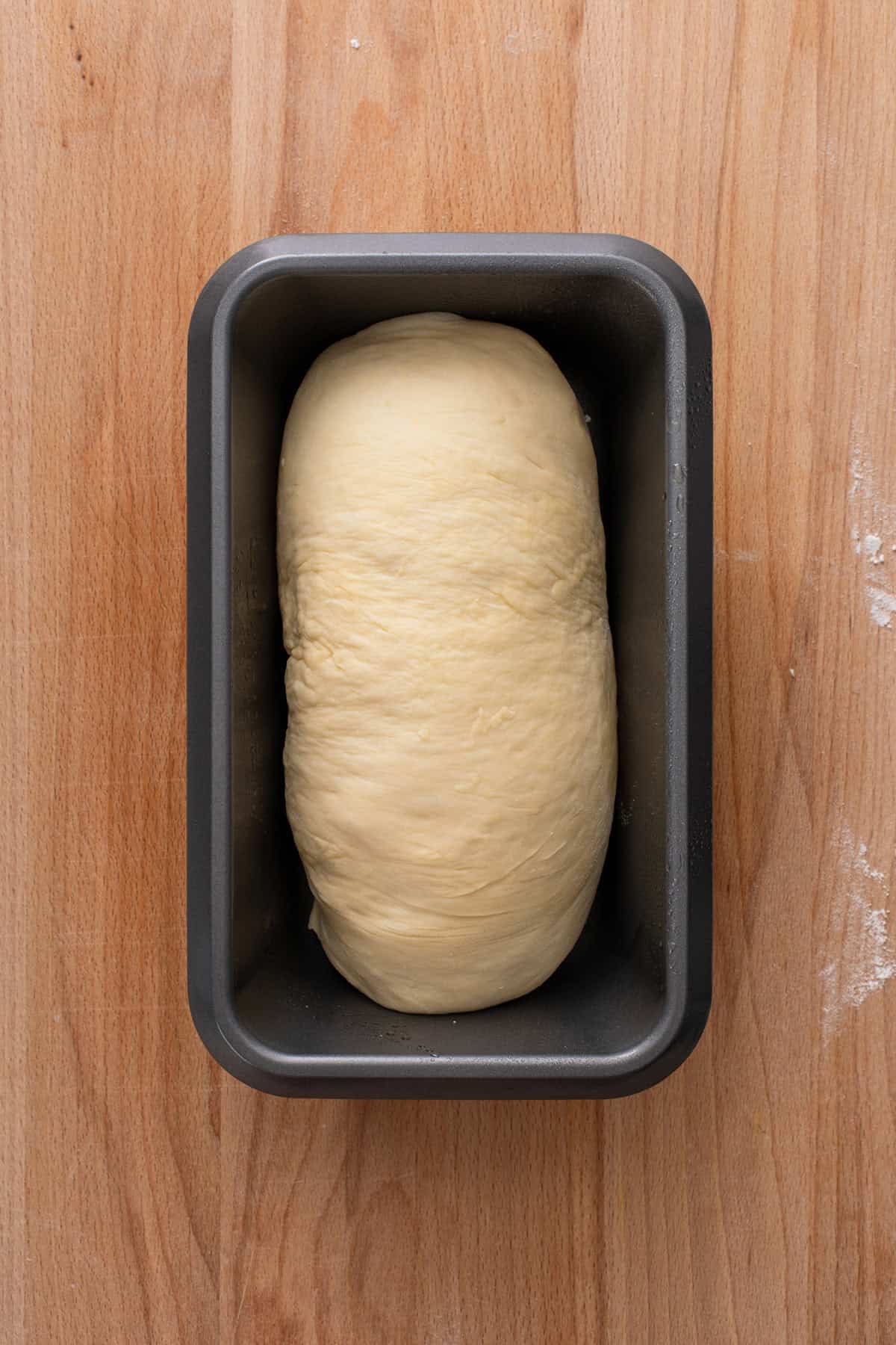 Shaped loaf of potato bread in a loaf pan.