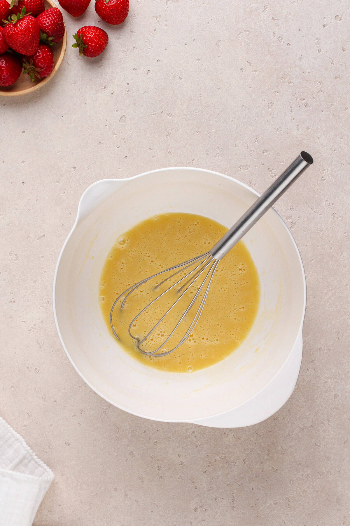 Wet ingredients for strawberry brownies whisked in a white bowl.