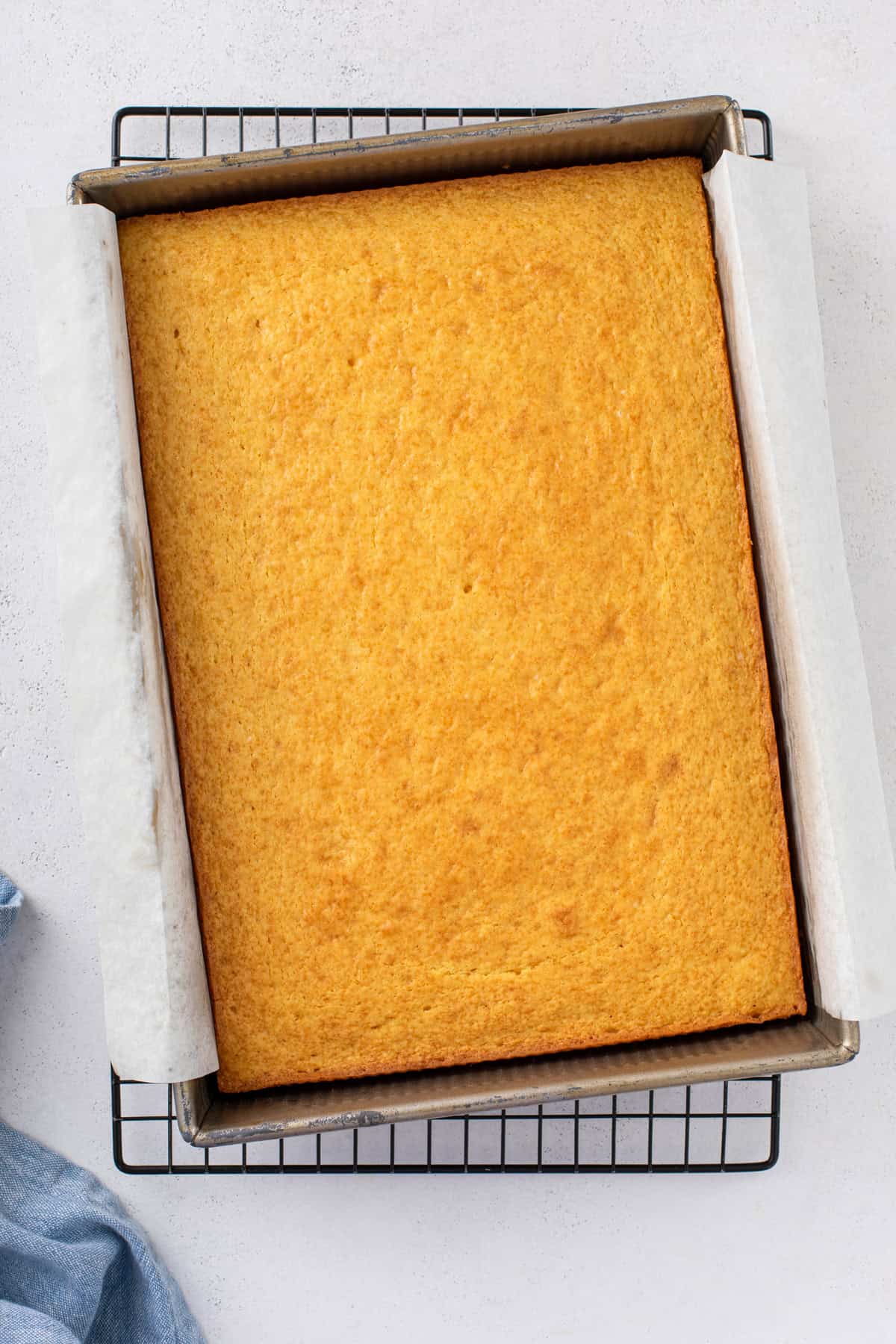 9x13-inch yellow sheet cake cooling in the pan on a wire rack.