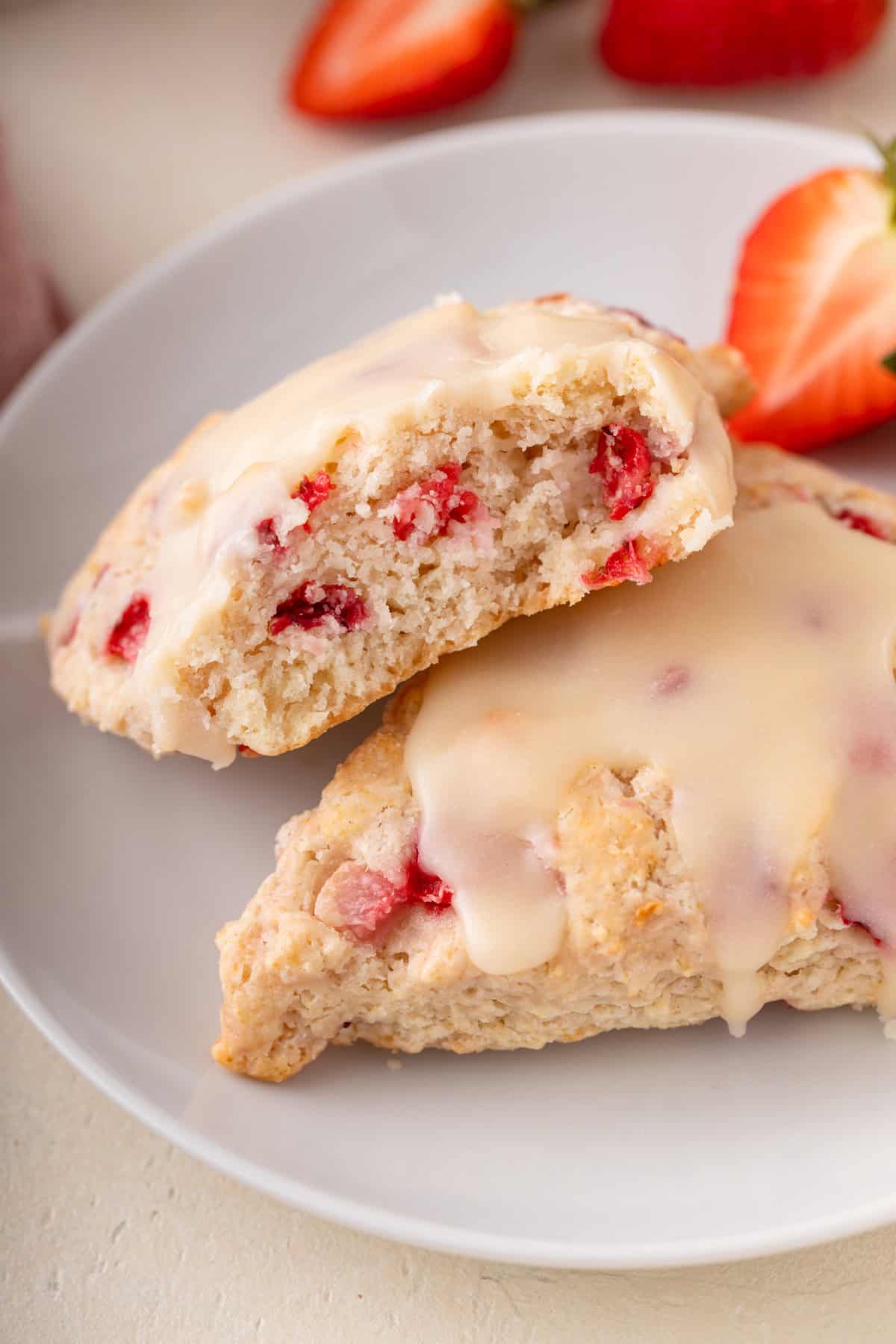 Close up of halved strawberry scone on a white plate to show the tender crumb.