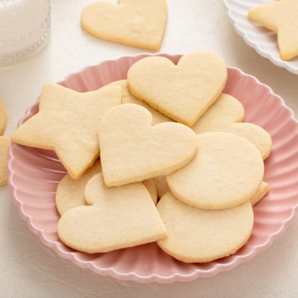 Several no-spread cut-out sugar cookies arranged on a pink plate.