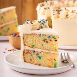 Slice of easy funfetti layer cake on a white plate.