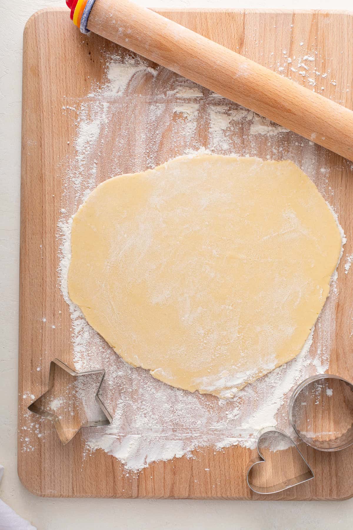 No-spread sugar cookie dough rolled out on a floured wooden board.