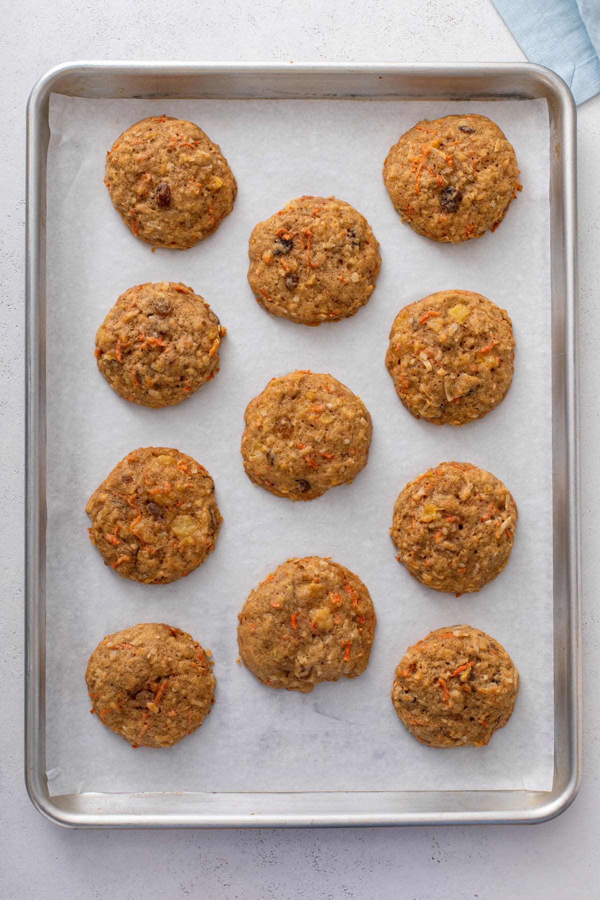 Baked carrot cake cookies cooling on a parchment-lined baking sheet.