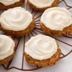 Frosted carrot cake cookies set on a decorative wire rack.