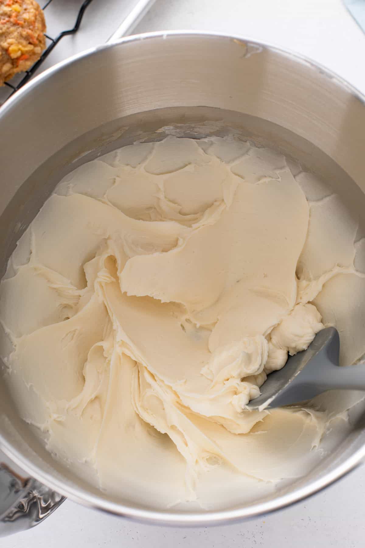 Cream cheese frosting for carrot cake cookies mixed in a metal bowl.