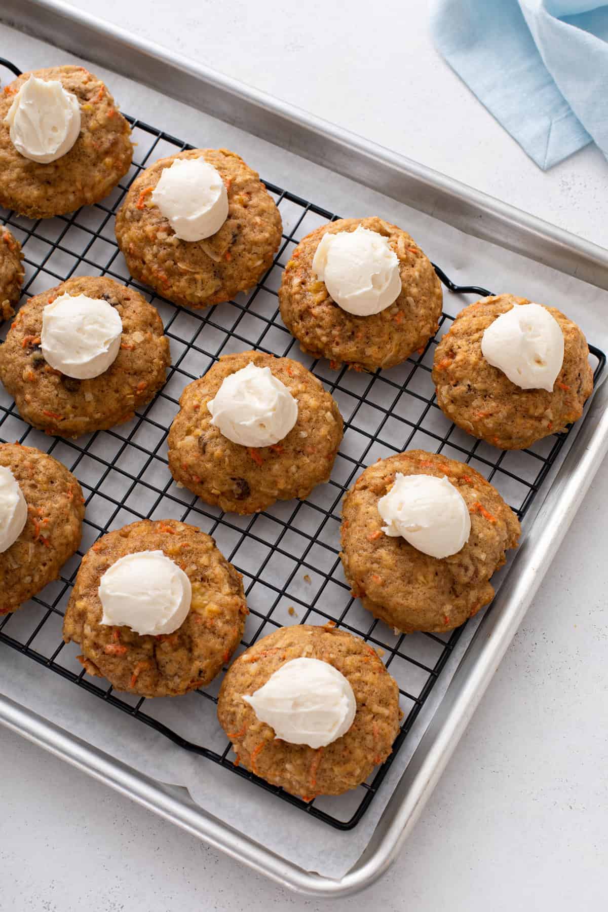 Small scoops of cream cheese frosting in the center of carrot cake cookies.
