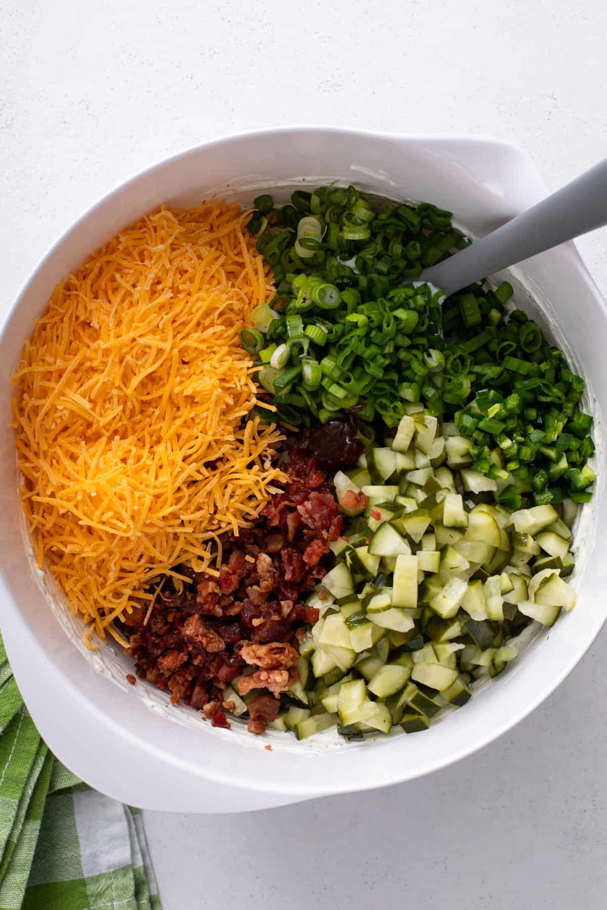 Mix-ins for pickle dip added to a white bowl.