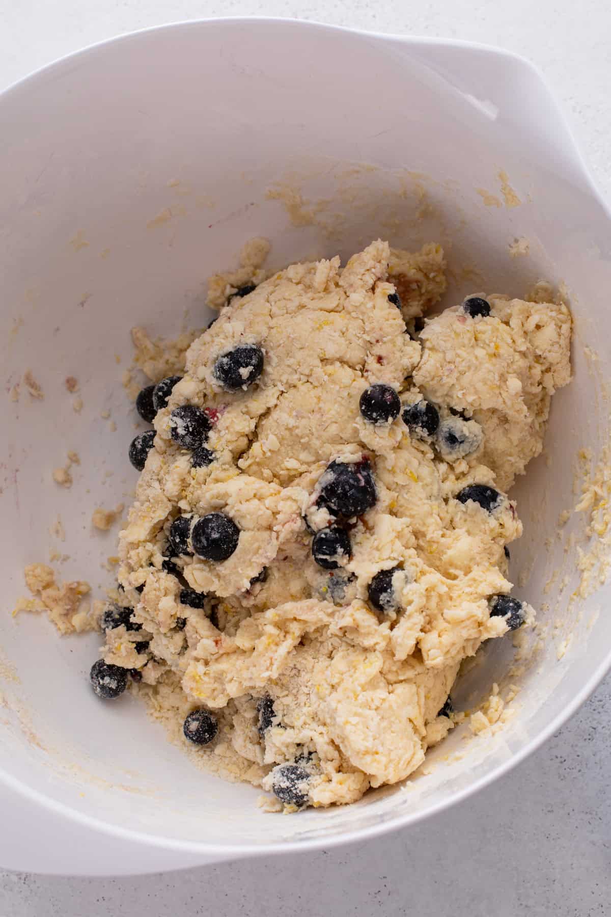 Lemon blueberry scone dough pressed into a rough ball in a white bowl.
