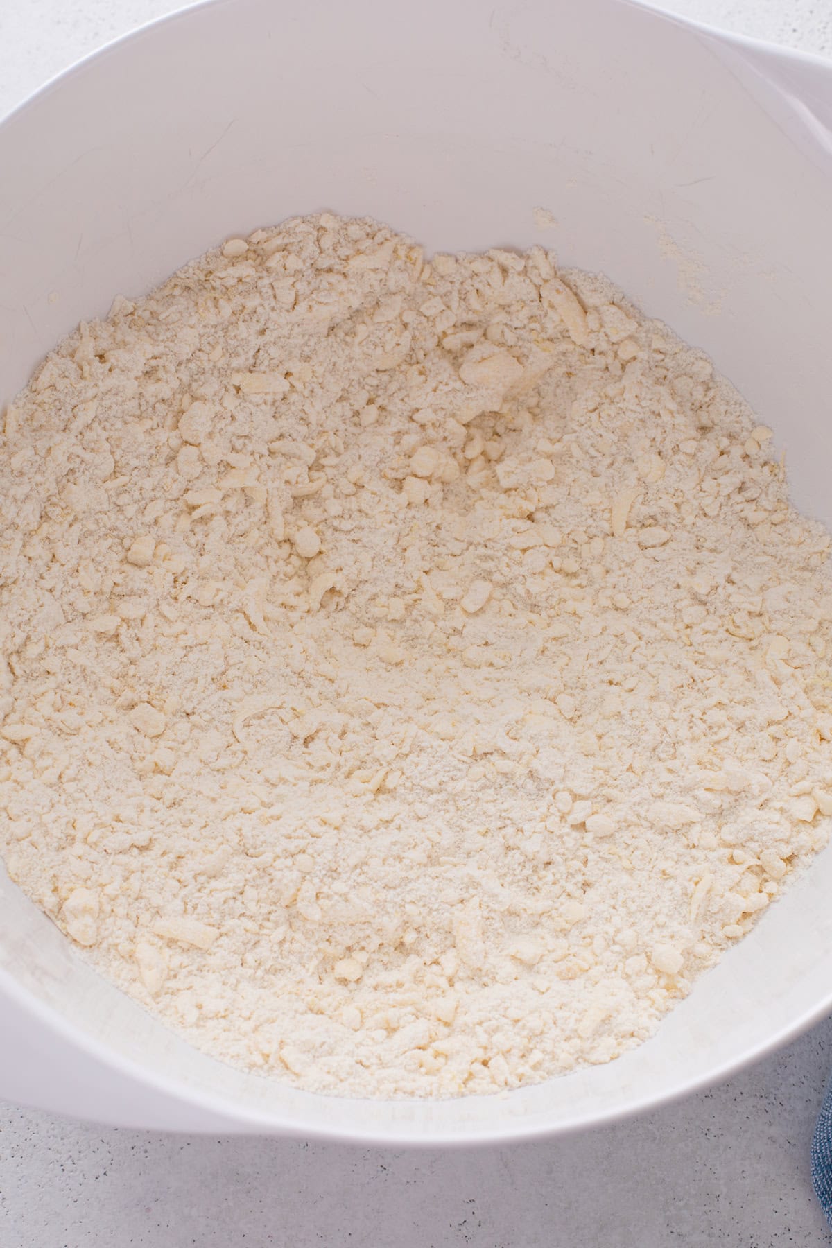 Grated butter worked into dry ingredients for scones, with the mixture resembling coarse meal.