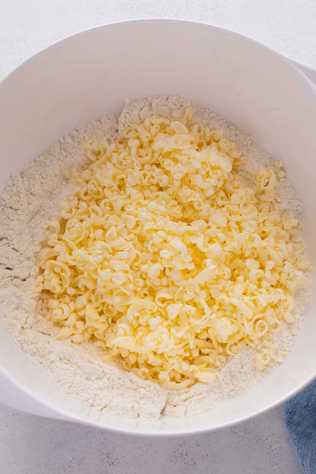 Butter grated into a mixing bowl with dry ingredients for scones.