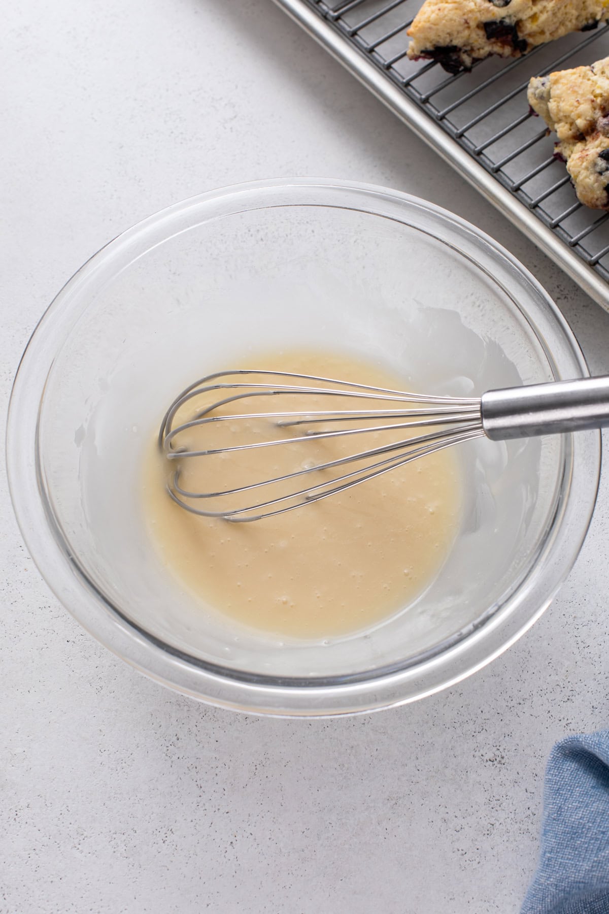 Lemon glaze for topping scones whisked in a glass bowl.