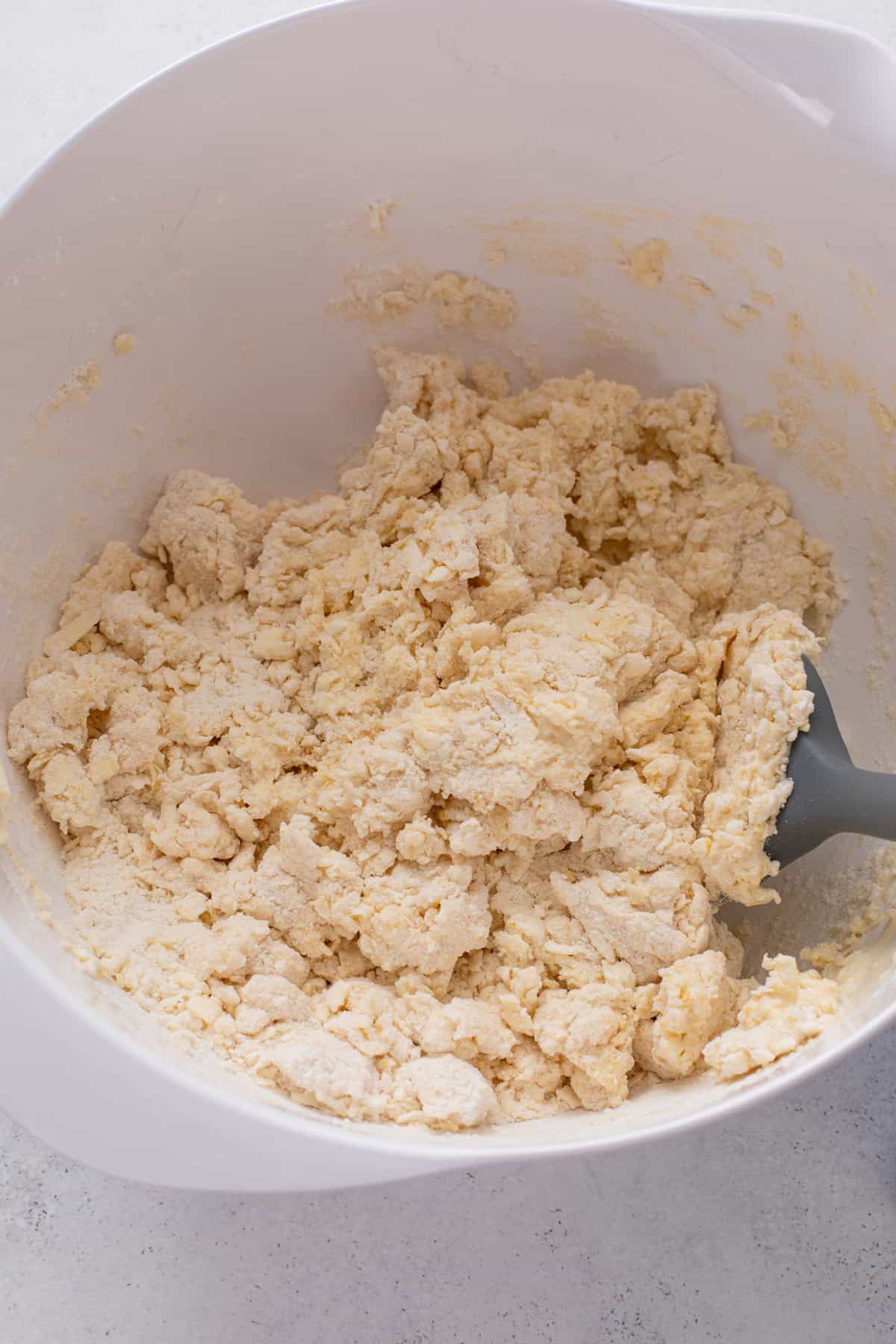 Dough base for lemon blueberry scones stirred together in a white bowl.