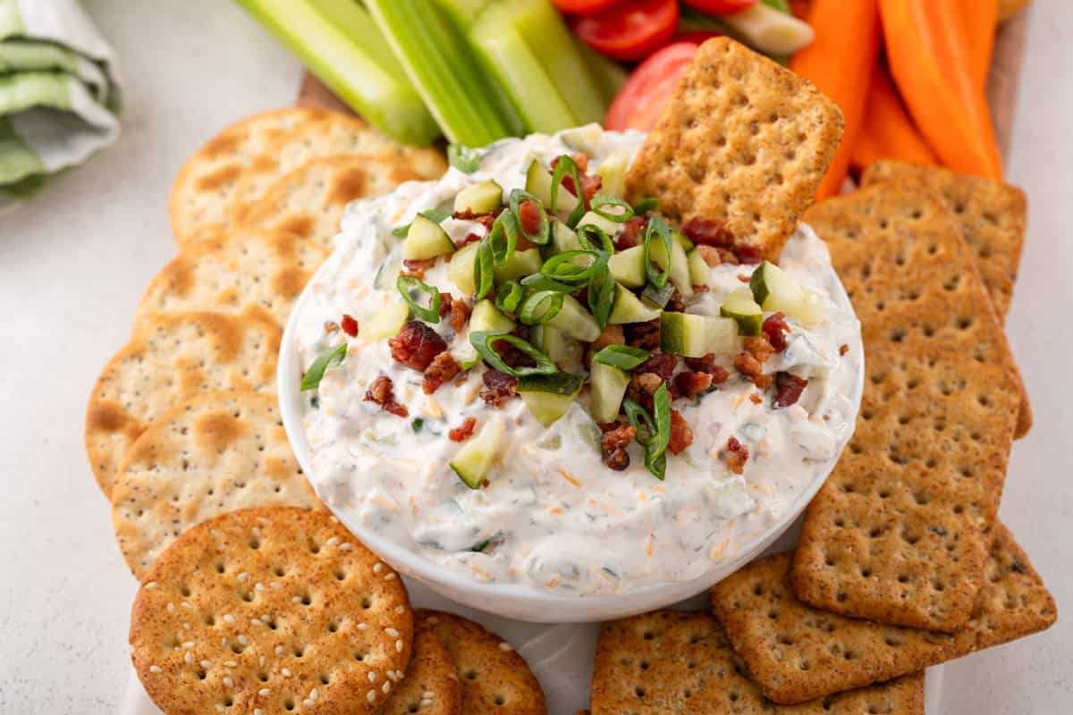 Cracker in a bowl of Grillo's pickle dip on a platter surrounded by crackers.