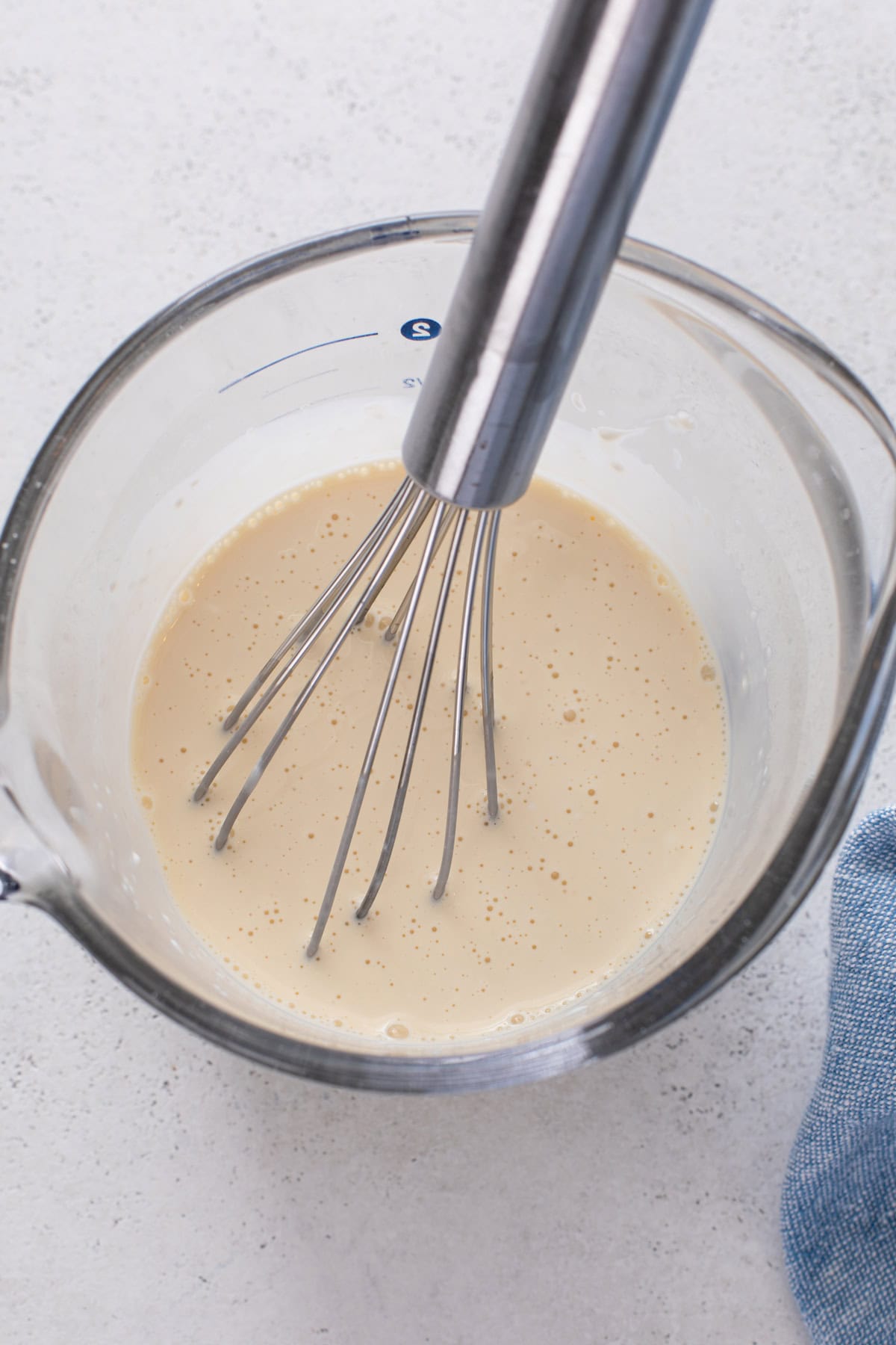 Wet ingredients for lemon blueberry scones whisked in a glass measuring cup.