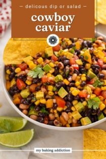 Cowboy caviar in a white serving bowl with two tortilla chips tucked into the edge of the dip. Text overlay includes recipe name.