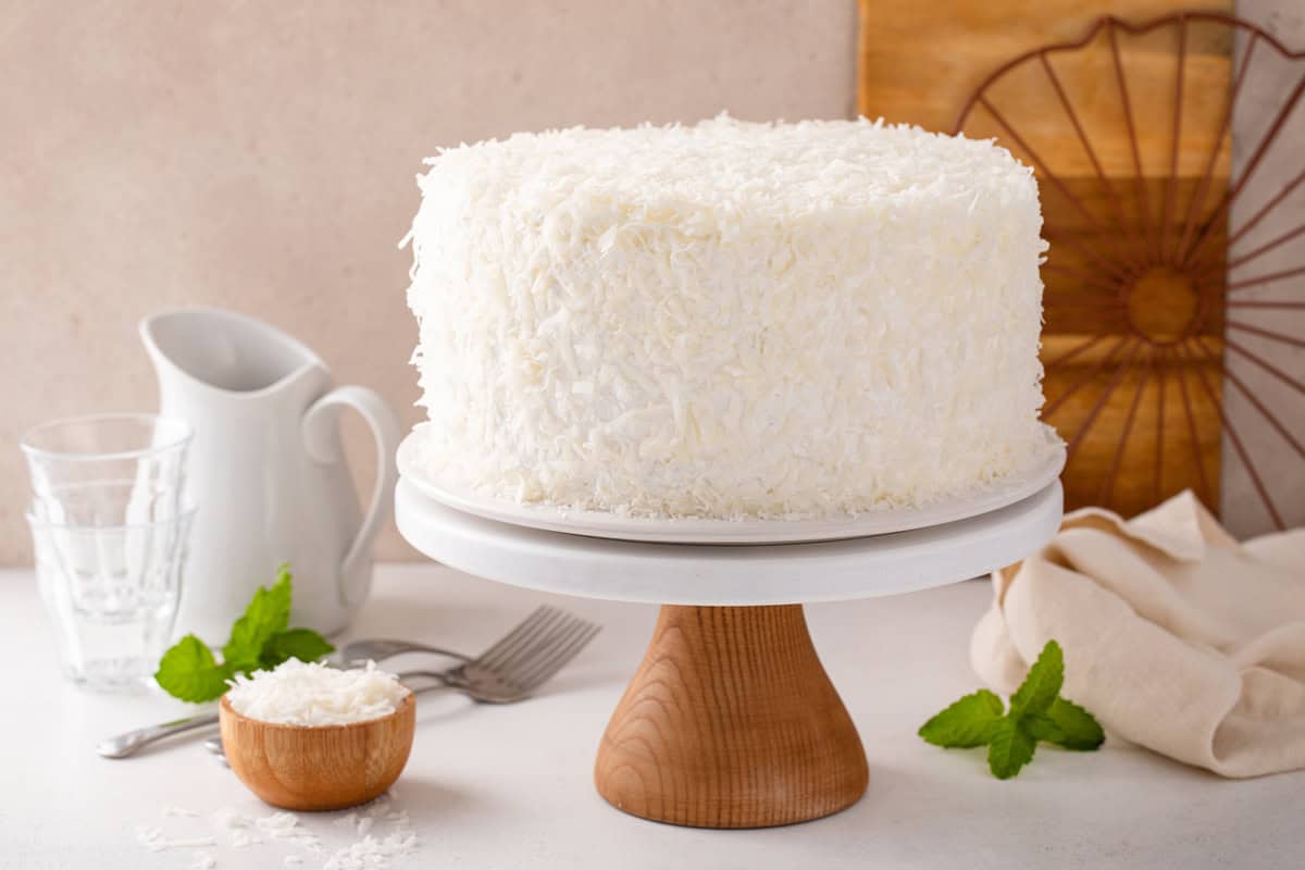 Side view of 3-day sour cream coconut cake on a cake stand.
