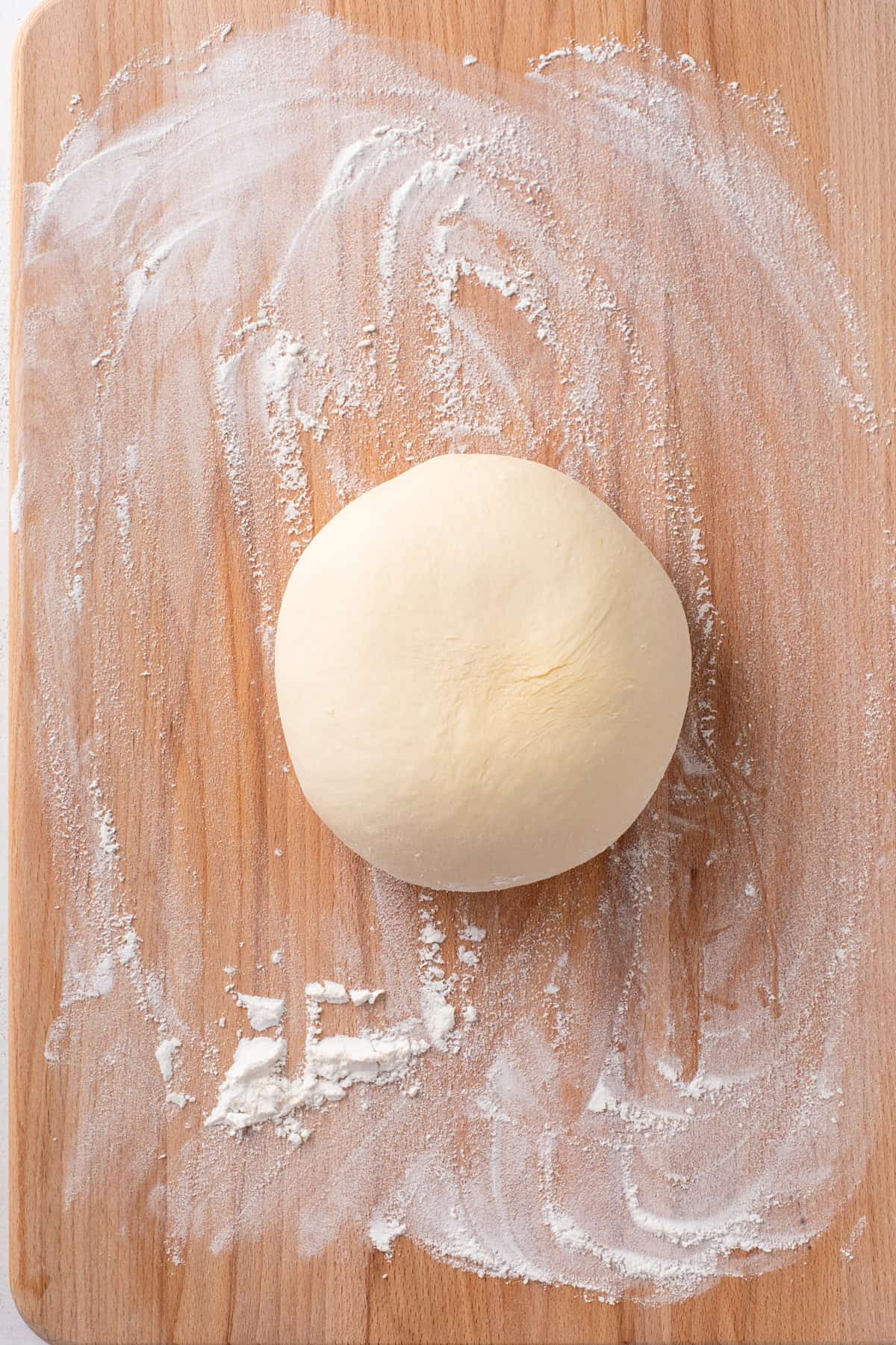 Kneaded sweet roll dough on a wooden surface.