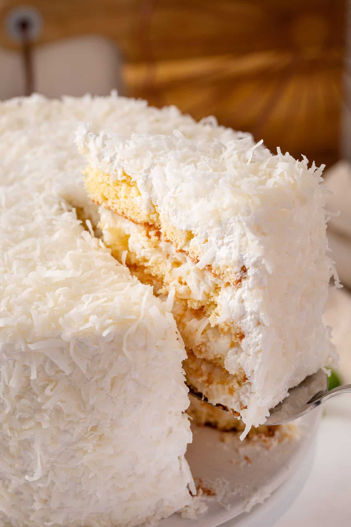 Cake server lifting up a slice of sour cream coconut cake.