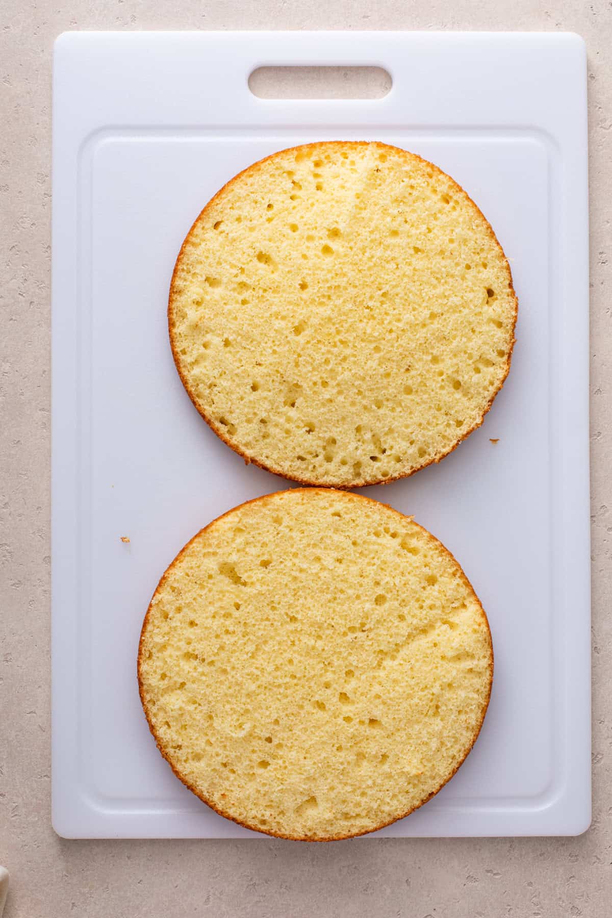 Layer of butter cake sliced in half and split open on a cutting board.