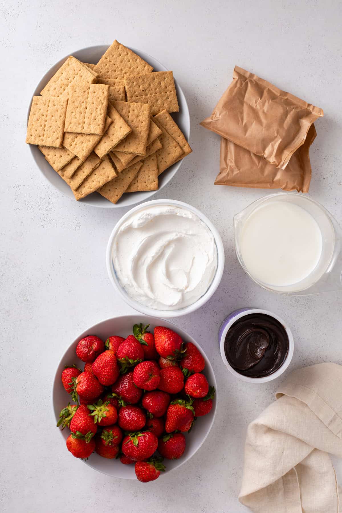 Ingredients for strawberry eclair cake arranged on a countertop.