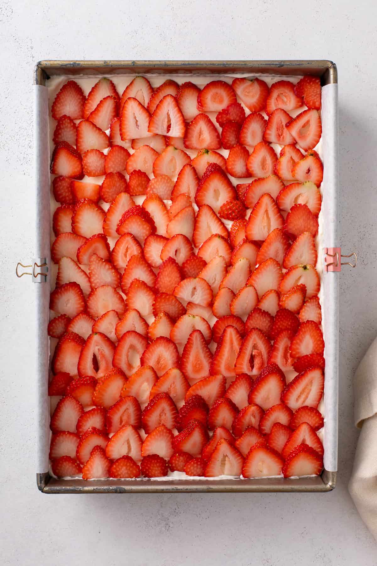 Sliced strawberries layered in a baking dish for strawberry eclair cake.
