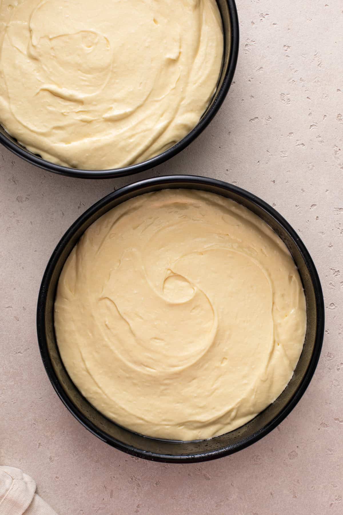 Butter cake batter divided between two round cake pans.