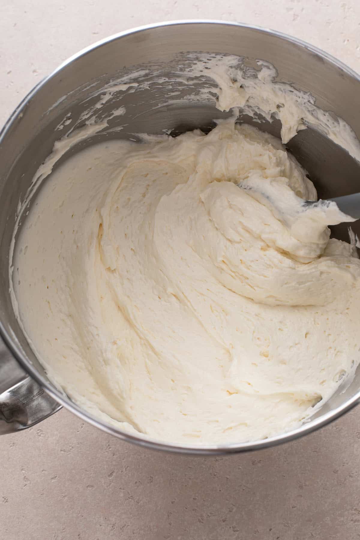 Cream cheese filling being mixed in a metal bowl.