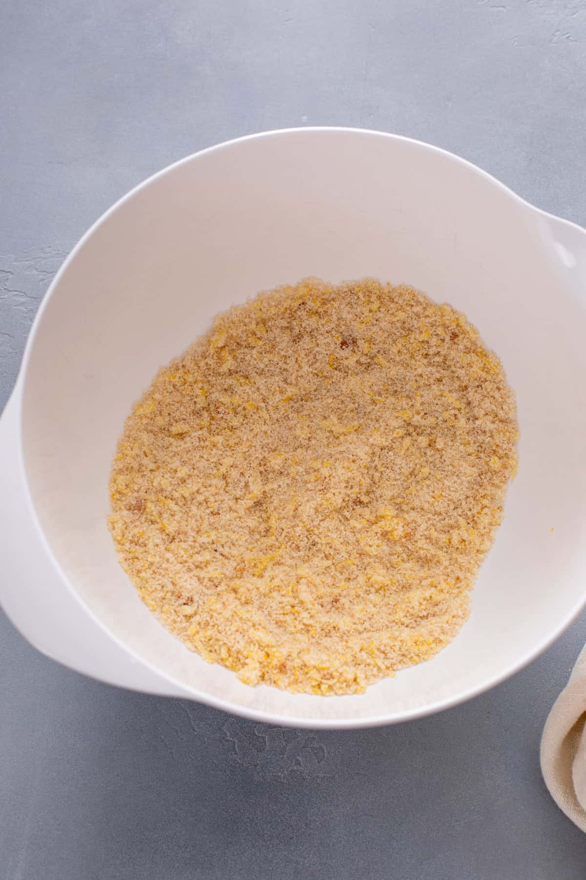 Lemon zest, granulated sugar, and brown sugar mixed together in a white bowl.